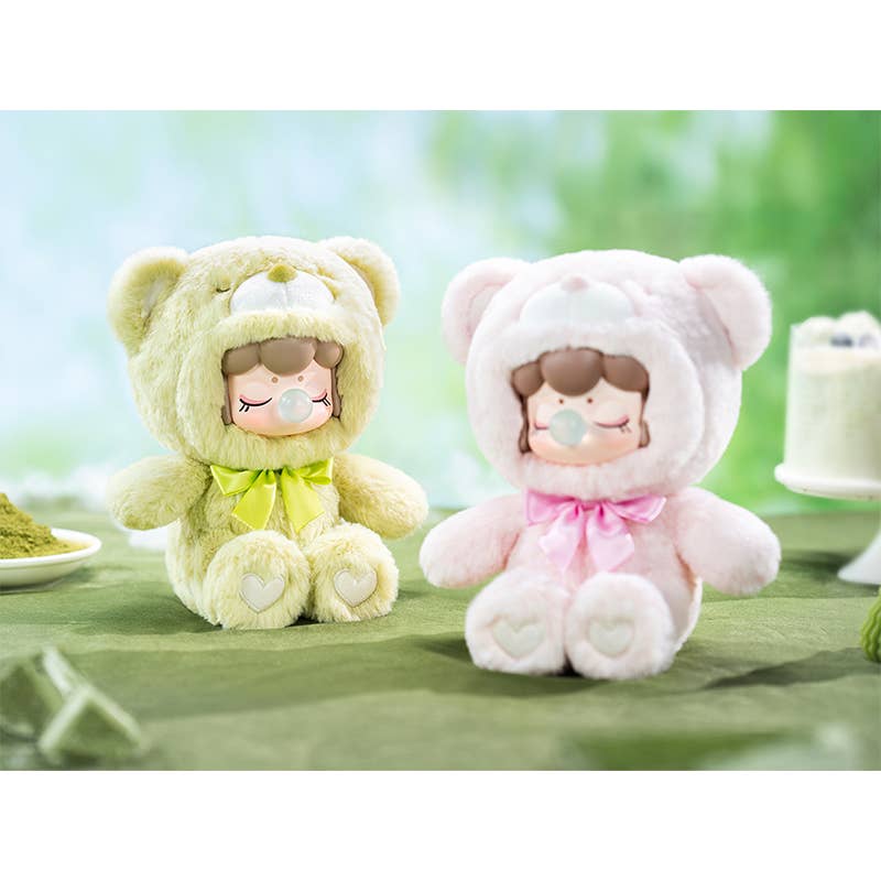 Two plush toys in bear costumes on a green surface with a blurred background